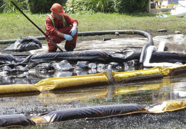 A worker monitors water in Talmadge Creek in Marshall Township, Mich., near the Kalamazoo River as oil from a ruptured pipeline, owned by Enbridge Inc., is trapped by booms on July 29, 2010. A suit filed Oct. 8, 2015, by the National Wildlife Federation says the federal Oil Pollution Act prohibits operators from handling, storing, or transporting oil until their spill response plans get federal approval. The plans are supposed to make sure enough resources are available to contain and remove spilled oil and limit environmental damage. (AP Photo/Paul Sancya, File)