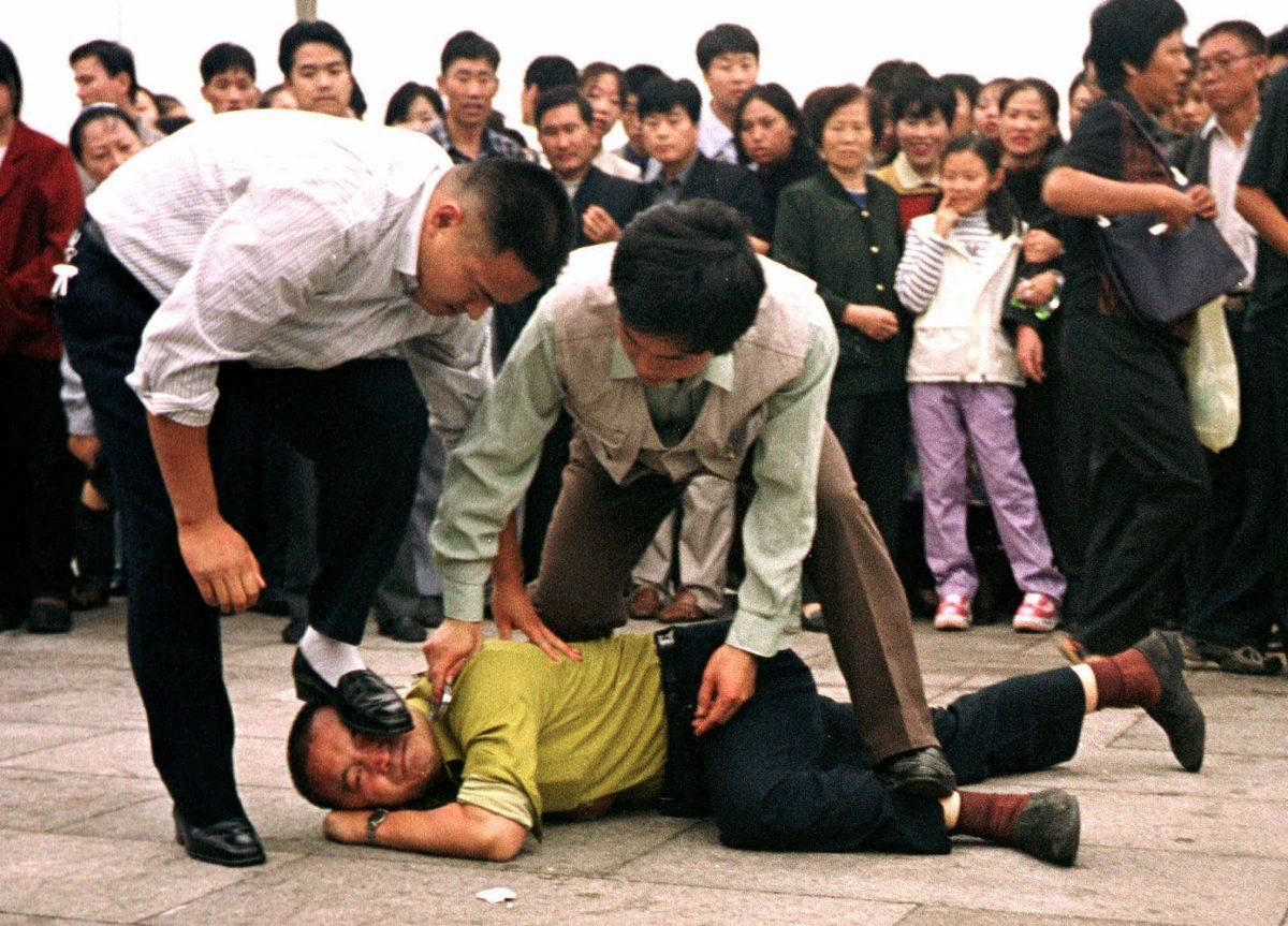 Police detain a Falun Gong protester in Tiananmen Square on Oct. 1, 2000. In January 2017, the Chinese regime appeared to publicly indicate that the persecution campaign remains an official policy. (AP Photo/Chien-min Chung)
