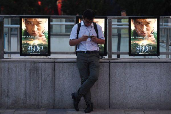 A man stands in front of movie posters for 'Wolf Warriors 2,' a domestic film with heavy nationalistic overtones, in Beijing, China on Aug. 7, 2017. (Greg Baker/AFP/Getty Images)