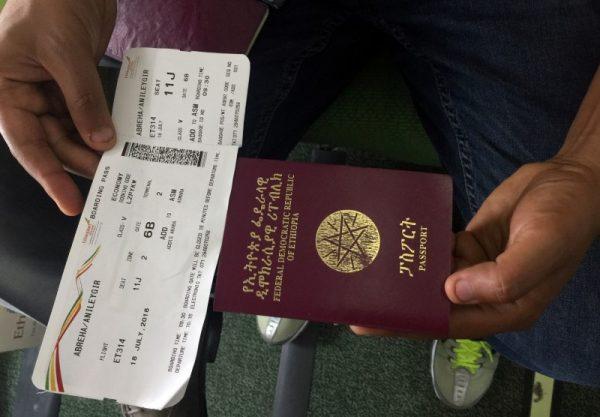 A passenger displays an Ethiopian passport and an Ethiopian Airlines boarding pass as he sits inside ET314 flight to Eritrea's capital Asmara at the Bole International Airport in Addis Ababa, Ethiopia July 18, 2018. (Reutes/Tiksa Negeri)