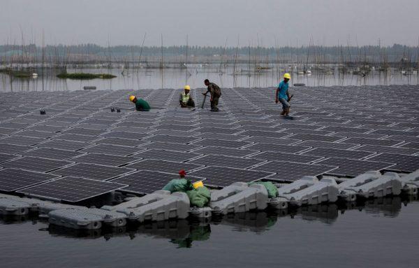 Chinese workers walk on a section of a large floating solar farm project under construction in Huainan, Anhui Province, on June 14, 2017. (Kevin Frayer/Getty Images)