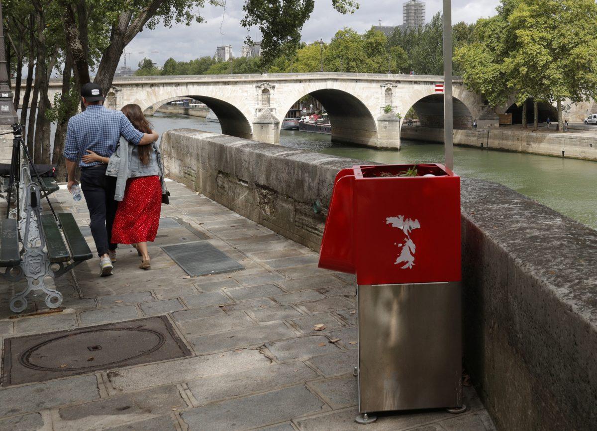 A couple walks near an eco-friendly urinal on the Ile Saint-Louis along the River Seine in Paris on Aug. 13, 2018. (Reuters/Philippe Wojazer)