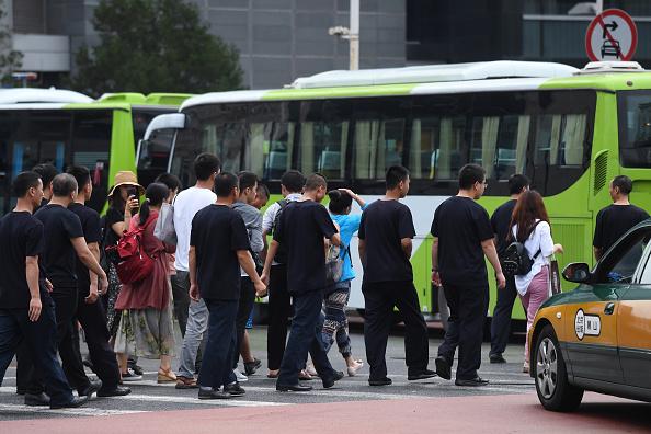 Petitioners who are victims of P2P lending scams are escorted to a bus by security personnel before being driven away in Beijing on Aug. 6, 2018. (GREG BAKER/AFP/Getty Images)