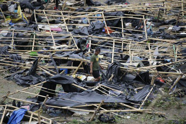 A policeman walks through makeshift tent shelters damaged by strong winds from Typhoon Mangkhut after it barreled across Tuguegarao city in Cagayan province, northeastern Philippines on Sept. 16, 2018. (AP Photo/Aaron Favila)