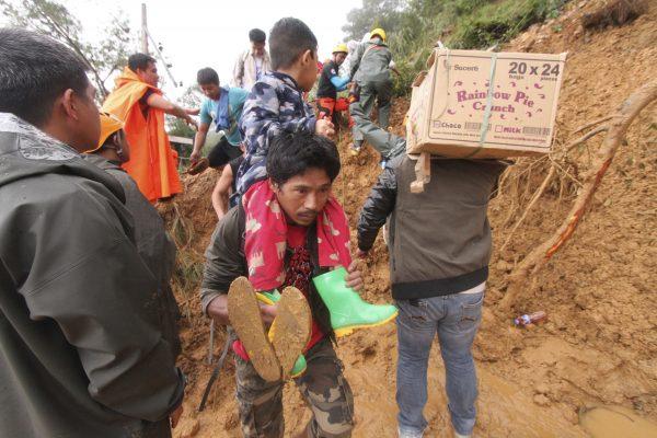 Families and relatives of miners in Itogon township, Benguet province in the northern Philippines, carry their belongings as they evacuate following landslides which were triggered by Typhoon Mangkhut burying an unknown number of miners and isolating the township Sept. 16, 2018. Typhoon Mangkhut barreled into southern China on Sept. 16 after lashing the northern Philippines with strong winds and heavy rain that left more than dozens dead from landslides and drownings. (AP Photo/Jayjay Landingin)