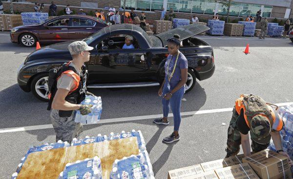 Members of the Civil Air Patrol load cars with MREs, (Meals Ready To Eat) water and tarps at distribution area in Wilmington, N.C., Sept. 18, 2018. (AP Photo/Chuck Burton)