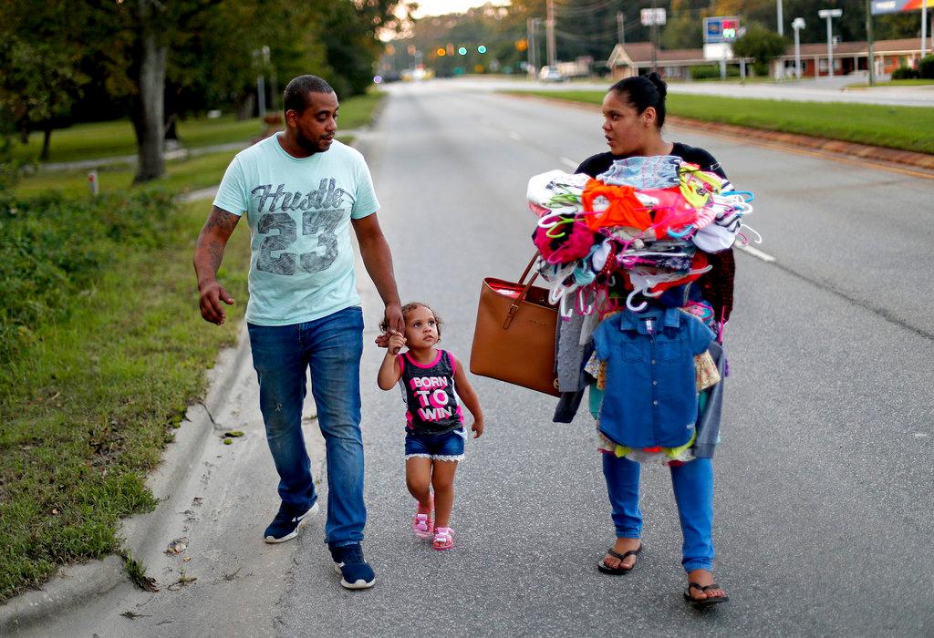 Jose Perez-Santiago (L) and Jose Perez-Santiago (L), Rosemary Acevedo-Gonzalez, walk with their daughter Jordalis, 2, after returning to their home for the first time since it was flooded in the aftermath of Hurricane Florence in Spring Lake, N.C., Sept. 19, 2018. (David Goldman/AP Photo)