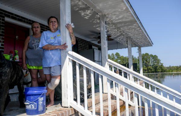 Candi Cisson, left, stands on the porch of the flooded home where she lives with her fiance Brian Terry on Bay Road Sept. 22, 2018, in Brittons Neck, S.C. Most houses were cut off completely Sept. 22, with water on the front steps and creeping closer to the porch. (Jason Lee/The Sun News via AP)