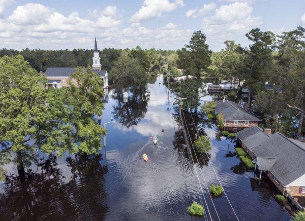 Kayaks on Long Avenue pass flooded sections of the Sherwood Drive community of Conway, S.C., on Sept. 23, 2018. (Jason Lee/The Sun News via AP)