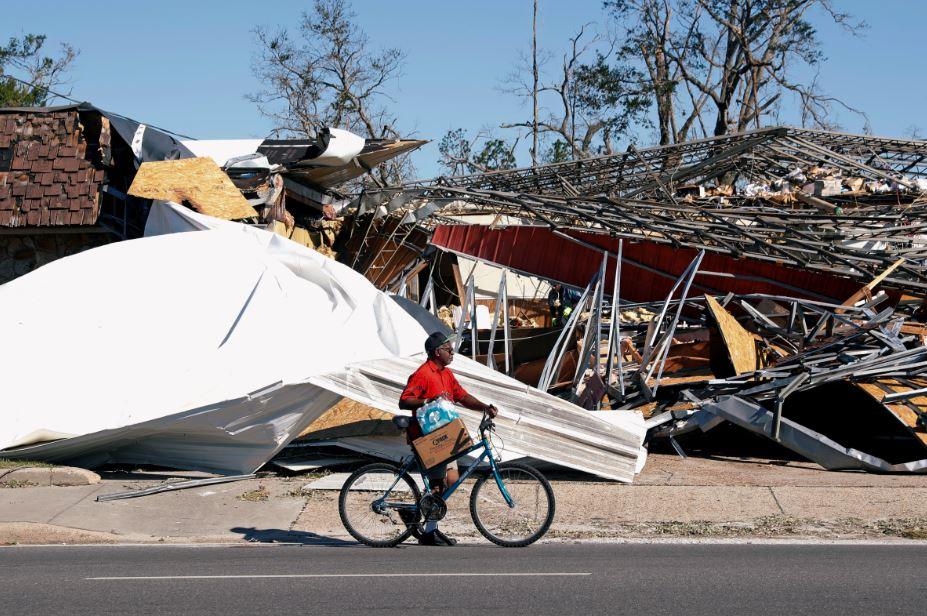 A man carries food and water past a building damaged by Hurricane Michael in PARKER, Fla., U.S., on Oct. 13, 2018. (Terray Sylvester/Reuters)