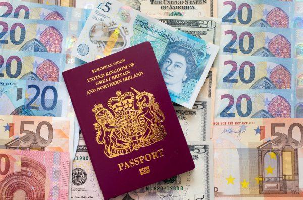 Euro, dollar, and pound sterling notes are seen beside a UK passport in Bath, England, on Oct. 10, 2016. (Matt Cardy/Getty Images)