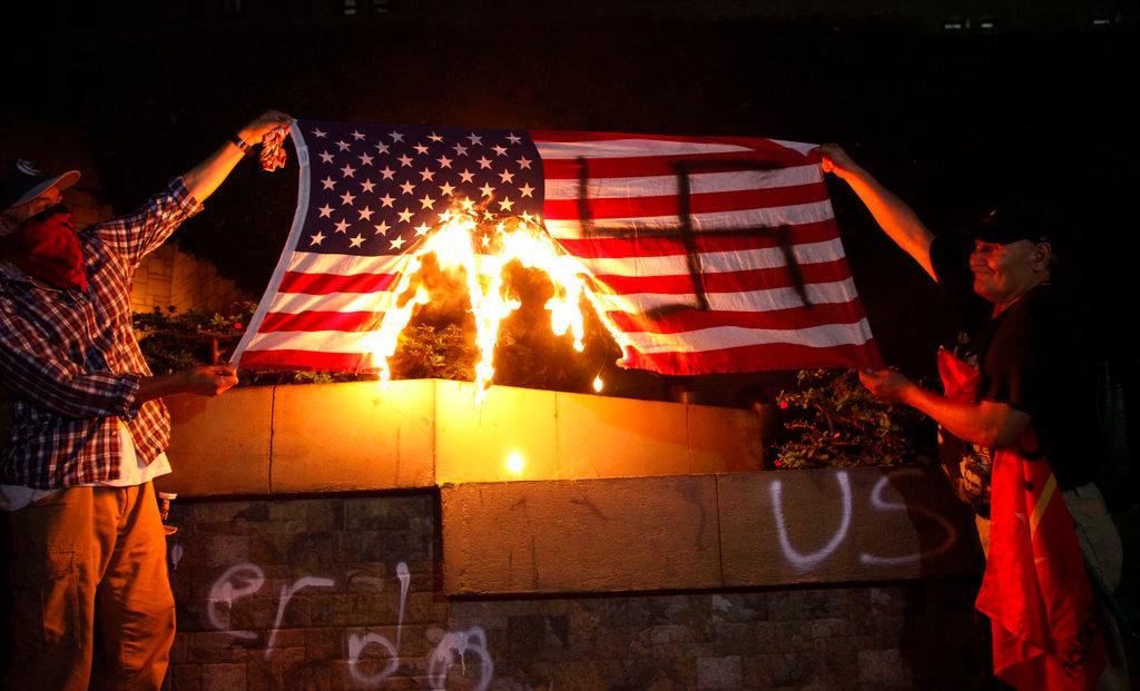 Two people burn a United States flag in front of the American Embassy, on Oct. 19, 2018, in Tegucigalpa, Honduras, during a protest in favor of the caravan of migrants that is currently stuck on the Guatemala-Mexico border. (Fernando Antonio/AP Photo)