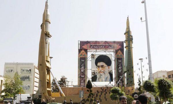 Iranians walk past Sejjil (L) and Qadr-H medium-range ballistic missiles displayed next to a portrait of Iranian Supreme Leader Ayatollah Ali Khamenei on Baharestan square in Tehran on Sept. 25, 2017. (Atta Kenare/AFP/Getty Images)