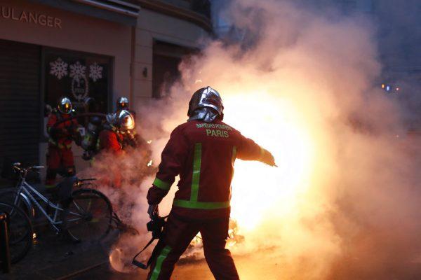Firefighters try to extinguished a car set on fire by demonstrators during clashes with riot police, in Paris, France, Saturday, Dec. 8, 2018. (AP Photo/Thibault Camus)