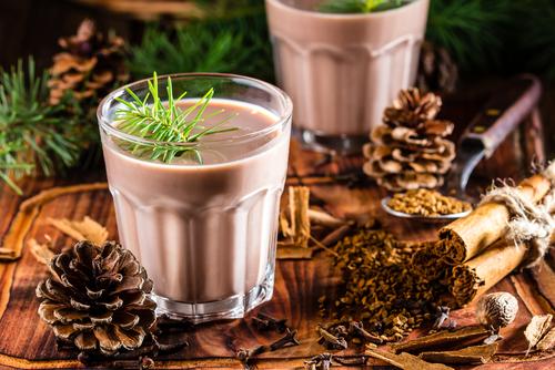 Traditional chilean alcohol Christmas drink Cola de mono - momkey tail with milk, aguardiente, cofee and spices on wooden board decorated fir tree brunches - Image. (Shutterstock)
