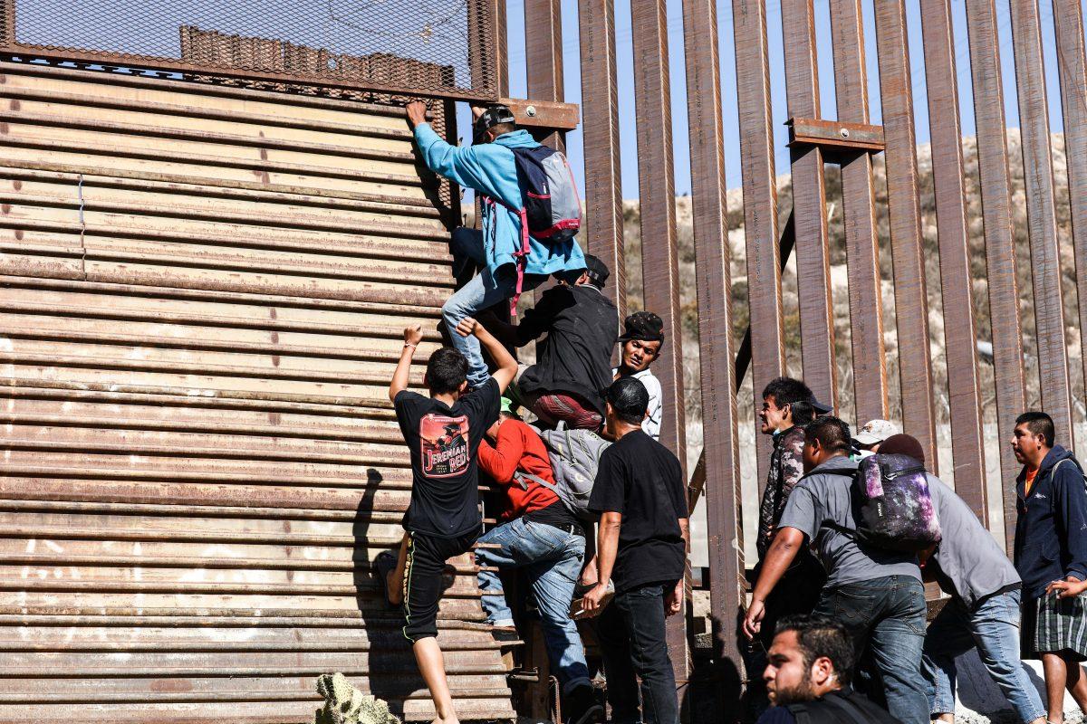 Migrants break through the U.S. border fence just beyond the east pedestrian entrance of the San Ysidro crossing in Tijuana, Mexico, on Nov. 25, 2018. (Charlotte Cuthbertson/The Epoch Times)