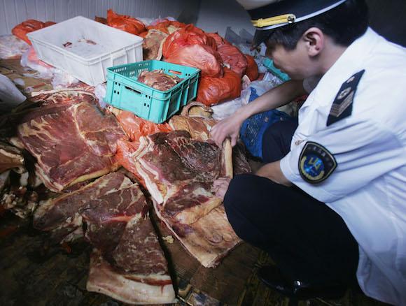 An officer with the Beijing Health Supervision Institute inspects spoiled pork. The Beijing Health Supervision Institute has confiscated over 2,000 kg spoiled pork from the market. (China Photos/Getty Images)