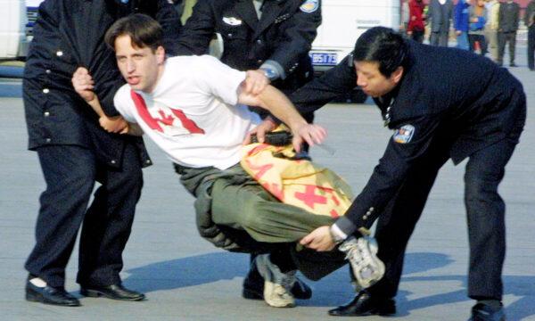 Chinese police officers take away a Canadian Falun Gong practitioner after he participated in a peaceful protest on Tiananmen Square in Beijing in November 2001. (Ng Han Guan/AP Photo)