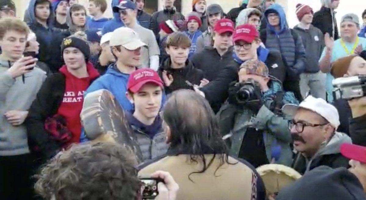 Nick Sandmann, wearing a "Make America Great Again" hat, stands looking at Nathan Phillips, a Native American and anti-President Donald Trump activist, after Philipps approached the Covington Catholic High School student in Washington, on Jan. 18, 2019. (Survival Media Agency via AP)