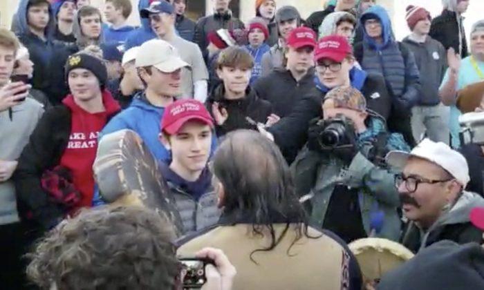 Nick Sandmann, wearing a "Make America Great Again" hat, looks at Nathan Phillips, a Native American anti-President Donald Trump activist, after Philipps approached the Covington Catholic High School student in Washington on Jan. 18, 2019. (Survival Media Agency via AP)