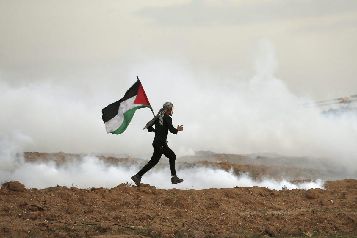 A man runs holding the Palestinian flag east of Gaza City near the Israeli border on Nov. 16, 2018. In previous weeks, Hamas instigated a number of violent protests on the Israeli border. (MAHMUD HAMS/AFP/Getty Images)