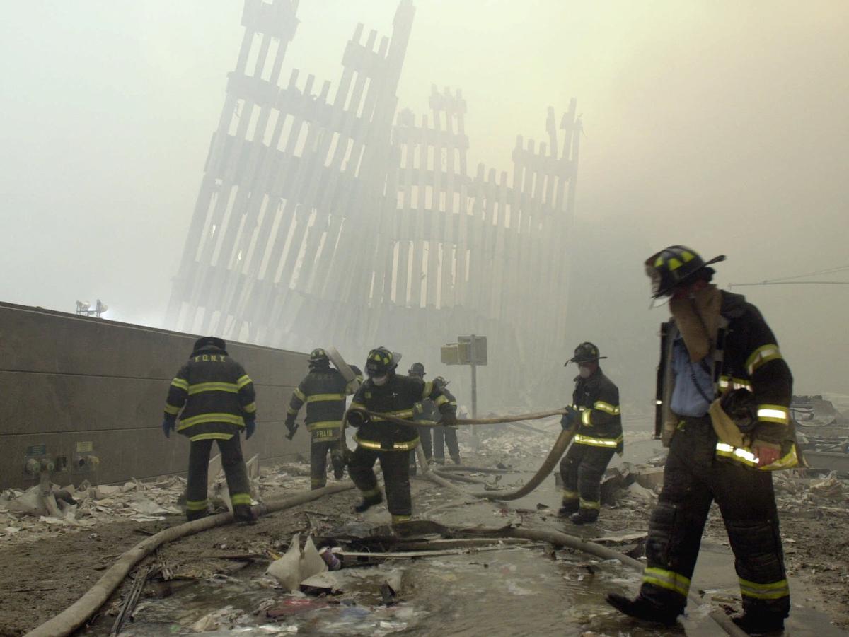 The skeleton of the World Trade Center twin towers in the background, New York City firefighters work amid debris on Cortlandt St. after the terrorist attacks on Sept. 11, 2001 (Mark Lennihan/AP)