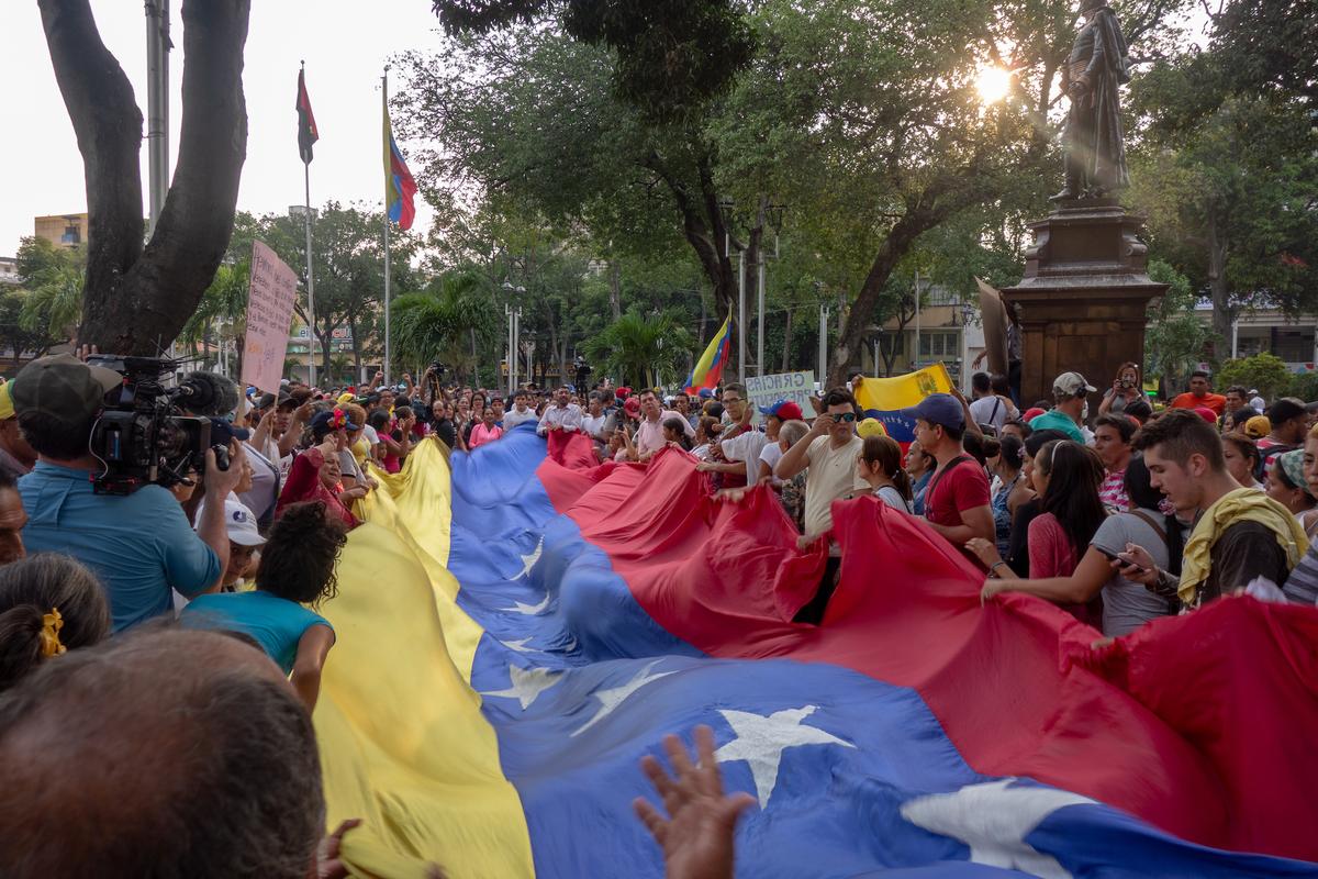 Venezuelan refugees unfurl their national flag after crossing the border into Cucuta, Colombia, on Feb. 12, 2019. (Luke Taylor)