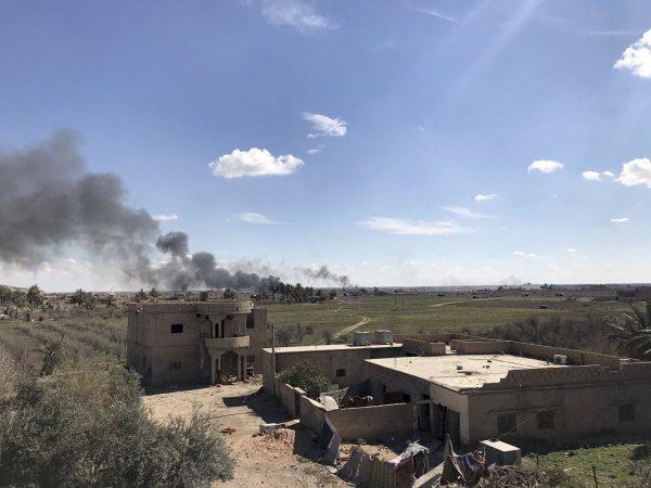 Columns of black smoke rise from the last small piece of territory held by ISIS terrorists as U.S. backed fighters pound the area with artillery fire and occasional airstrikes, as seen from outside Baghouz, Syria, on March 3, 2019. (Sarah El-Deeb/AP)