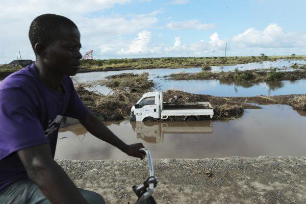 A man cycles past a truck swept away by Cyclone Idai in Nyamatanda about 50 kilometers from Beira, in Mozambique, on March, 21, 2019. (Tsvangirayi Mukwazhi/AP Photo)