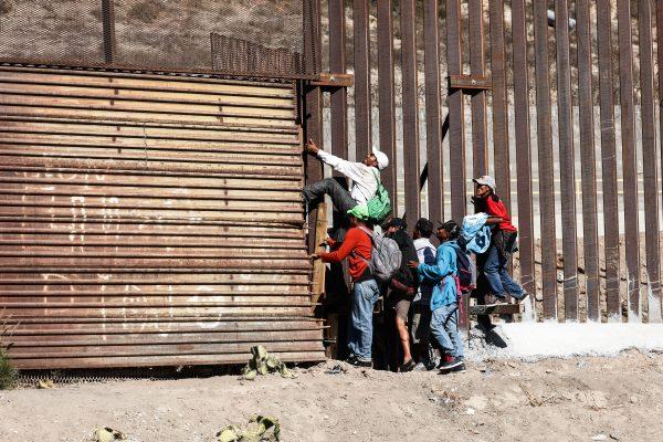 Migrants break through the old U.S. border fence just beyond the east pedestrian entrance of the San Ysidro crossing in Tijuana, Mexico, on Nov. 25, 2018. (Charlotte Cuthbertson/The Epoch Times)