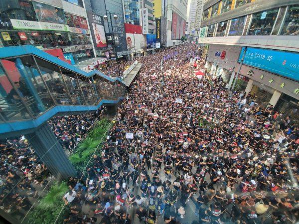 Protesters pass Hysan Place, a shopping mall and office building, at Causeway Bay, Hong Kong on June 16, 2019. (Li Yi/The Epoch Times)