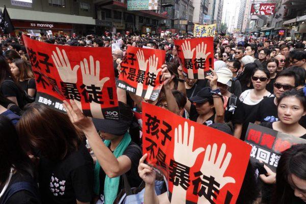 Protesters hold up Chinese signs that read “Children Are Not Rioters” in a march in Hong Kong on June 16, 2019. (Yu Gang/The Epoch Times)