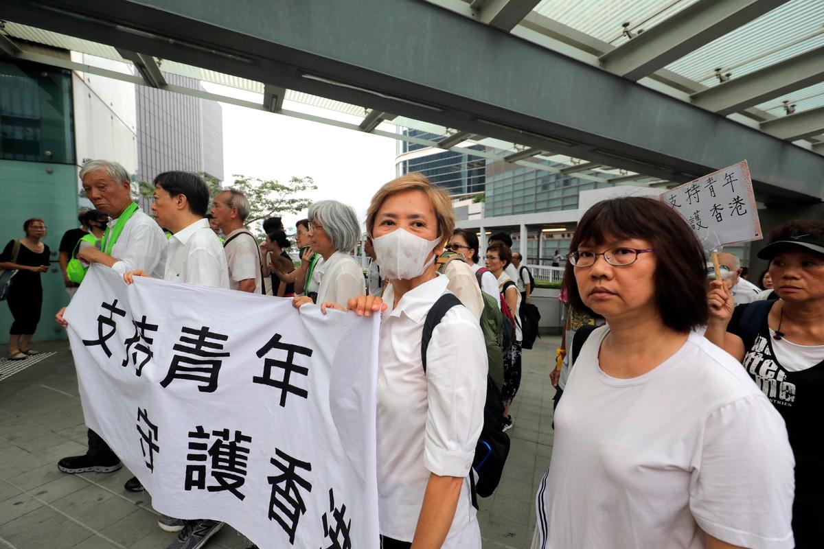 Veteran actress and singer Deanie Ip, center, wears a mask as she holds a banner in support of young people during a march in Hong Kong on July 17, 2019. (AP)