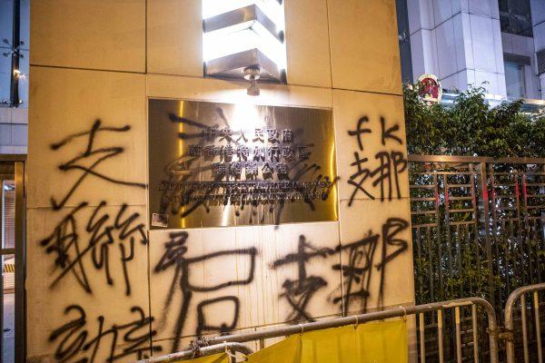 The entrance sign of China's Liaison Office in Hong Kong is covered by graffiti painted by protesters following a largely peaceful march against a controversial extradition bill in Hong Kong on July 21, 2019. (Yu Kong/The Epoch Times)
