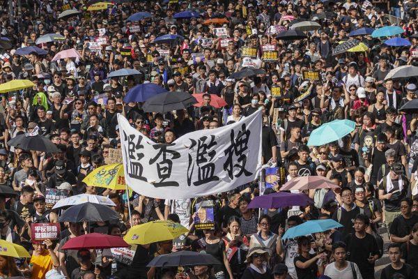 Protesters march against a controversial extradition bill in Hong Kong on July 21, 2019. The large banner shown here condemns the police for abuse of force. (Yu Kong/The Epoch Times)