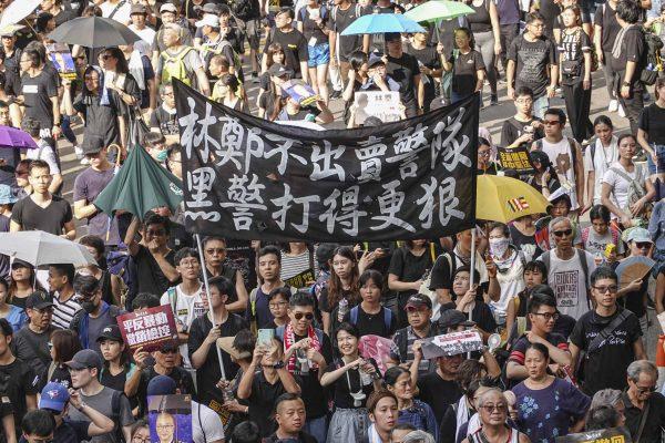Protesters march against a controversial extradition bill in Hong Kong on July 21, 2019. The large banner shown here condemns city leader Carrie Lam and the city’s police force. (Yu Kong/The Epoch Times)