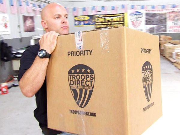 Aaron Negherbon carrying a box of supplies. (Courtesy of Troops Direct)