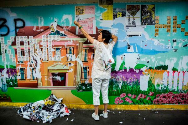 A woman takes down posters put up by anti-government protesters as part of a Lennon Walls in the Mong Kok district of Hong Kong on Sept. 21, 2019, after a campaign by a pro-government politician to encourage people to start clearing and cleaning Lennon Walls that are spread throughout the city. (Issac Lawrence/AFP/Getty Images)