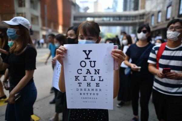 A protester holds a placard, mimicking an eye chart that reads "you can kill the dreamer but you can't kill the dream", marches with others from Chater Garden towards Central district in Hong Kong on Oct. 2, 2019. (Mohd Rasfan/AFP via Getty Images)