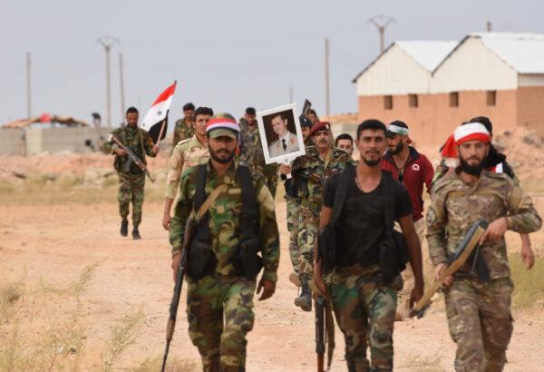 Syrian government forces raise a national flag and an image of President Bashar al-Assad at Tabqa air base in norther Syria's Raqa region on Oct.16, 2019. Assad's troops have returned to key northern areas for the first time in years in a deal with the Kurds, seeking protection after President Donald Trump ordered the withdrawal of American forces. (AFP via Getty Images)