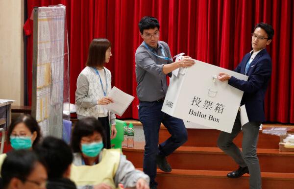 Polling officials carry a ballot box to count the votes of the Hong Kong council elections, in a polling station in Hong Kong, on Nov. 24, 2019. (Adnan Abidi/Reuters)