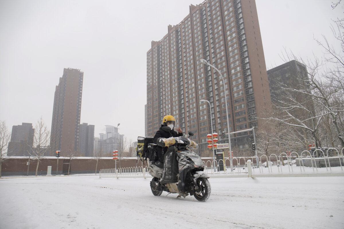 A food delivery worker rides his bike amid snow at a residential compound in Beijing on Feb. 6, 2020. (Reuters)