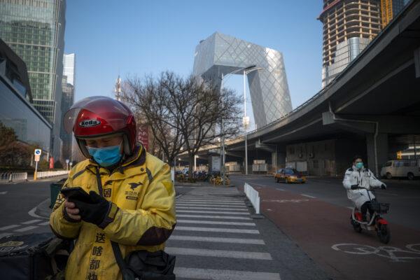 A delivery man uses his phone in the streets of the busy Central Business District in Beijing, China, on Feb. 10, 2020. (Andrea Verdelli/Getty Images)