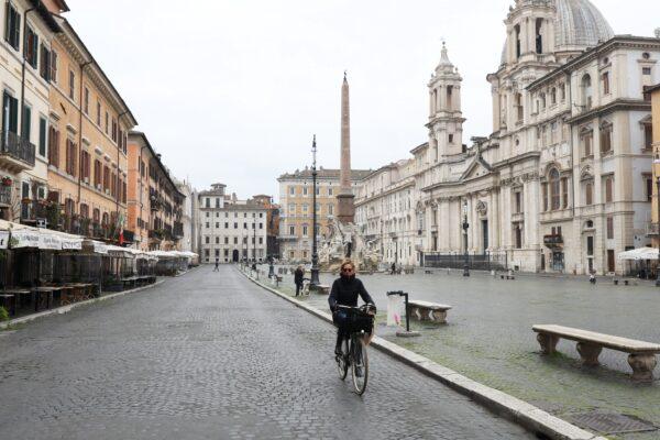 A woman is seen cycling in a completely empty Navona Square in Rome, on March 13, 2020. The city's streets were eerily quiet on the second day of a nationwide shuttering of schools, shops, and other public places. (Marco Di Lauro/Getty Images)