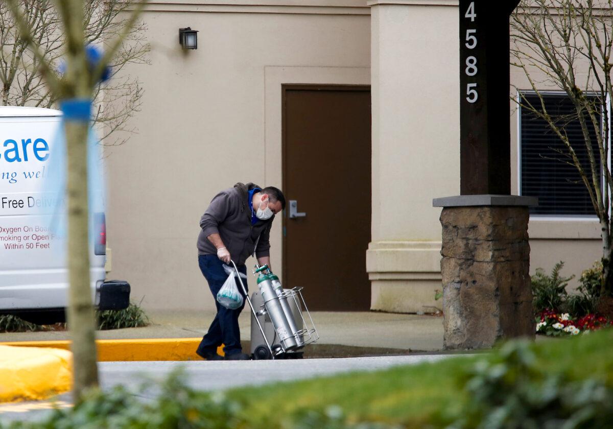 A man from a Bellevue Healthcare van wheels in oxygen tanks at an assisted living facility linked to several cases of COVID-19 outbreak in Redmond, Washington, on March 21, 2020. (Reuters/Lindsey Wasson)