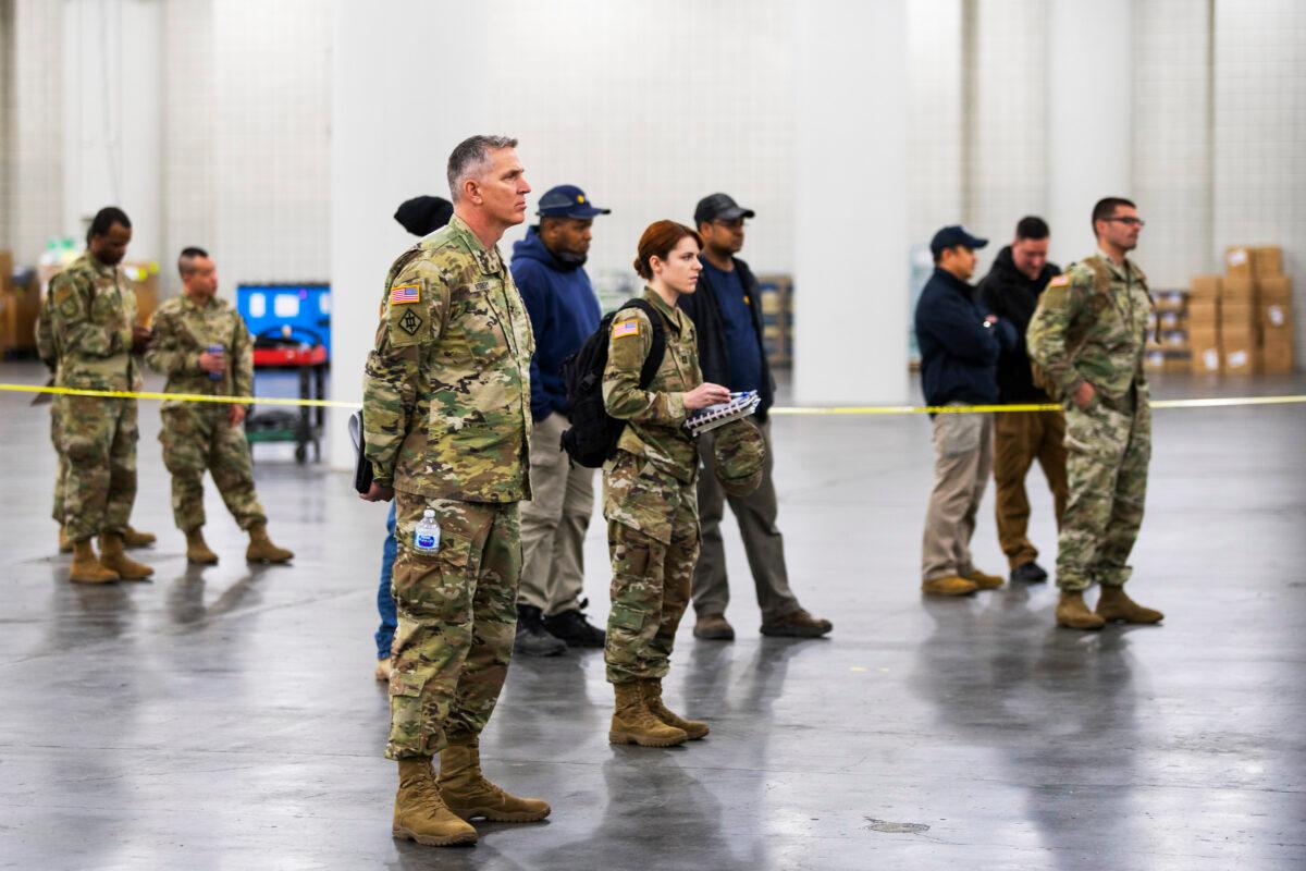 Members of the National Guard listen to New York Governor Andrew Cuomo as he speaks to the media at the Javits Convention Center, which is being turned into a hospital in New York City on March 24, 2020. Eduardo Munoz Alvarez/Getty Images)