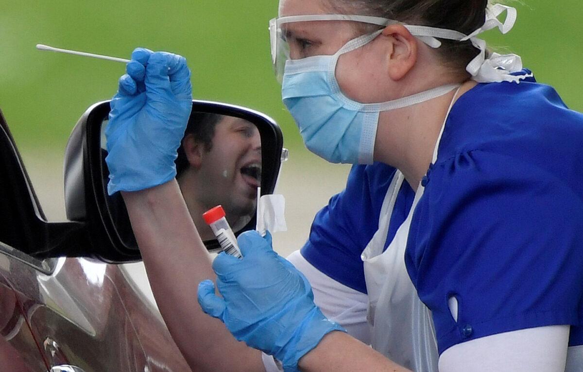 Medical staff are seen testing people at a COVID-19 test centre in Chessington, UK, on April 2, 2020. (Toby Melville/Reuters)