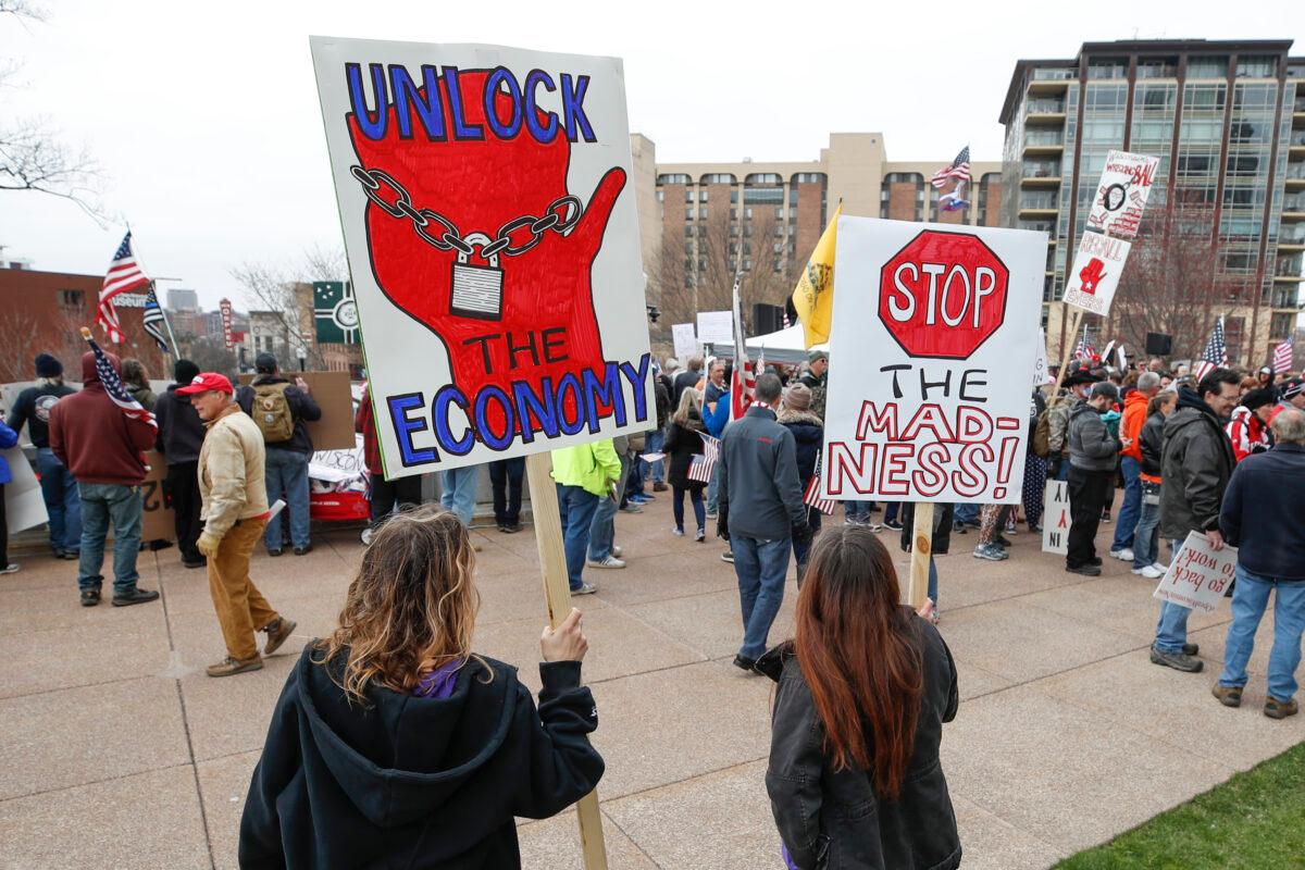 People hold signs during a protest against the CCP virus shutdown in front of the State Capitol in Madison, Wis., on April 24, 2020. (Kamil Krzaczynski/AFP via Getty Images)