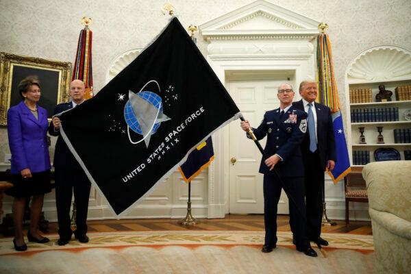 President Donald Trump stands as chief of space operations as U.S. Space Force Gen. John Raymond (2nd from left) and Chief Master Sgt. Roger Towberman (1st from right) hold the U.S. Space Force flag as it is presented in the Oval Office on May 15, 2020. Secretary of the Air Force Barbara Barrett stands to the far left. (Alex Brandon/AP Photo)