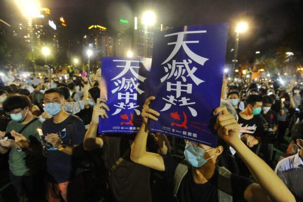 People hold up placards with the words “The Heavens Will Destroy the Chinese Communist Party” at a vigil at Victoria Park, Hong Kong, on June 4, 2020. (Song Bilung/The Epoch Times)